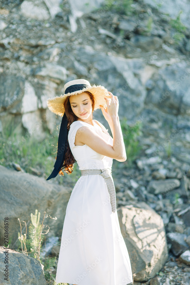 Summer photo shoot in the Park at the rocks and stones. Beautiful girl in white dress and hat. Summer photo shoot in the Park at the rocks and stones. Beautiful girl in white dress and hat.