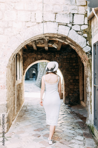 Summer photo shoot on the streets of Kotor, Montenegro. Beautiful girl in white dress and hat. © pavelvozmischev