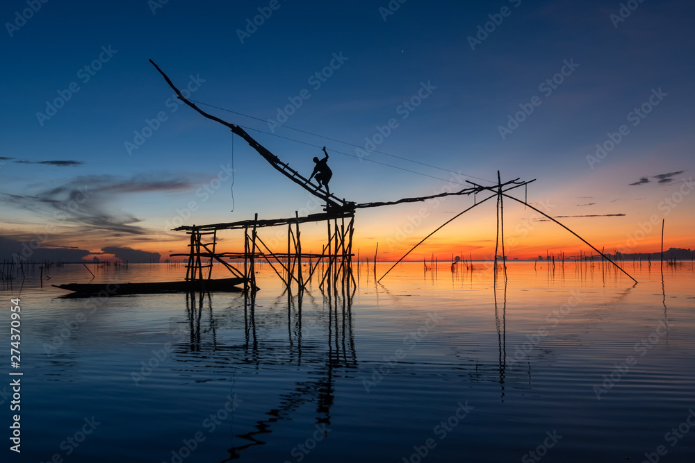 Giant fishing gear and fisherman working in the beautiful morning light at Pakpra canal, Thailand.
