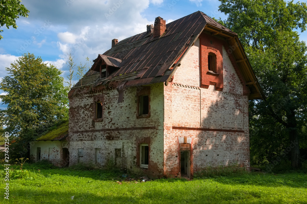 Collapsing two-story brick house in the park on a summer day Collapsing two-story brick house in the park on a summer day