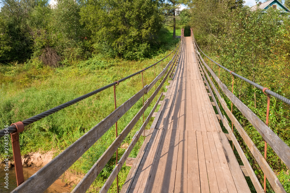 Fototapeta premium Suspension bridge over the river Belaya in the village of Lyubytino Novgorod region