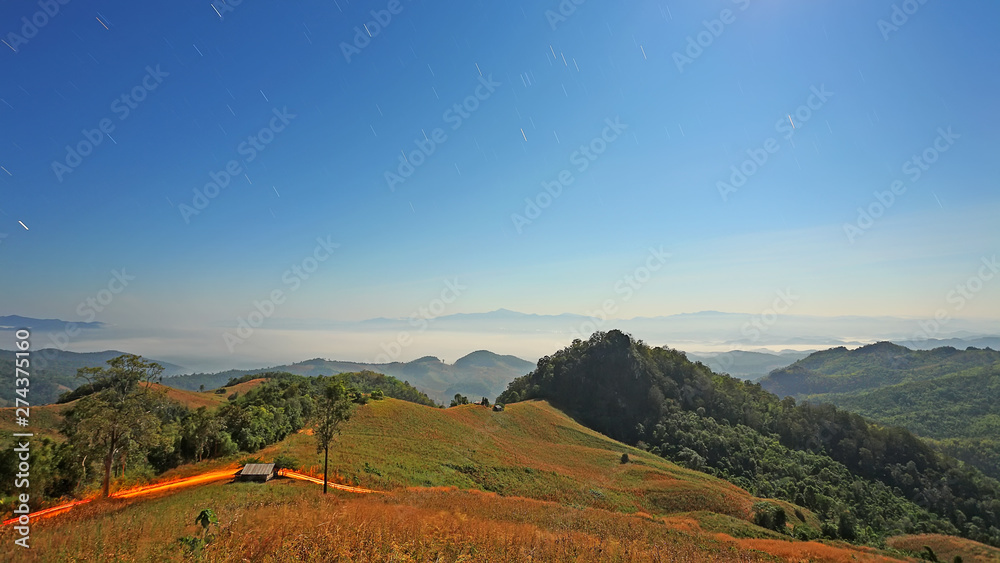 Starry night sky of beautiful mountains range with mist in the during the light of the full moon at sri nan national park or doi sa mer dao, tourist attraction at Nan Province, northern of Thailand