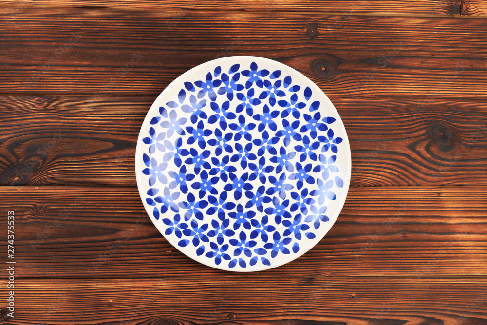 painted plate in blue flower on wooden  background .