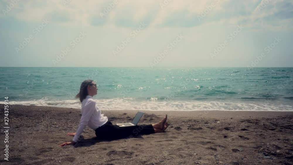 successful business woman with a mobile phone working in a laptop sitting on the beach. concept - vacation. toned image. successful business woman with a mobile phone working in a laptop sitting on the beach. concept - vacation. toned image.