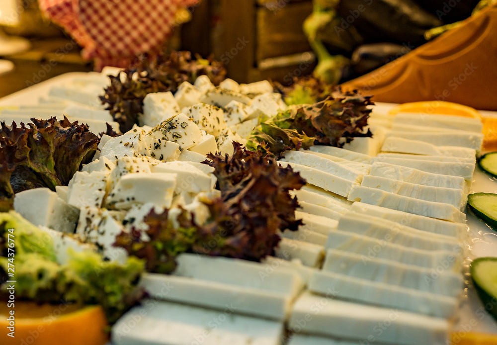 Dish to the dinner table. A dish of vegetables and cheese slicing on the table.