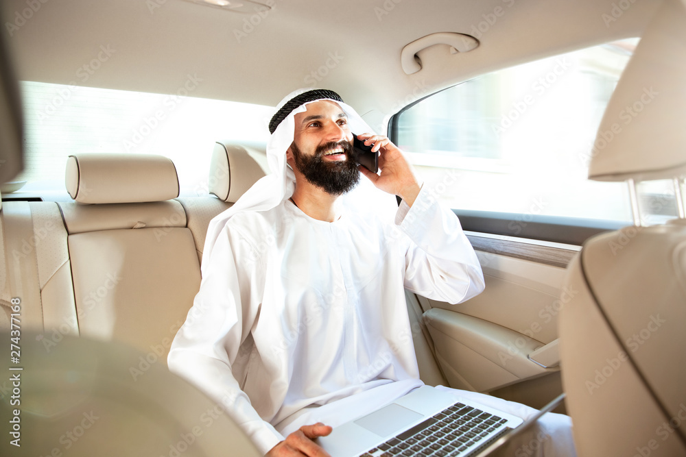 Arab saudi businessman working online with a smartphone, calling his clients or partners in his car. Male model as an enterpreneur. Concept of business, finance, modern technologies, start up, economy