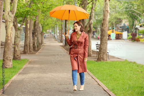 Beautiful young woman with umbrella outdoors on rainy day