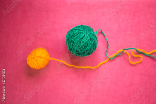 Two balls of wool on a pink background.