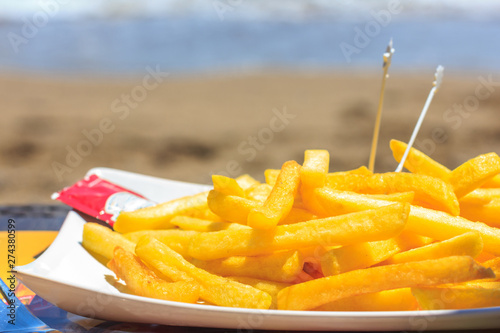 Fototapeta Naklejka Na Ścianę i Meble -  Fried french fries on the beach against the background of the sea