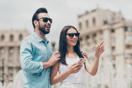 Portrait excited nice charming cute lovely youth touch shoulders sign index finger hold hand user smartphone cellphone smart cell phone mobile eyewear eyeglasses specs shirt blue white dress skirt