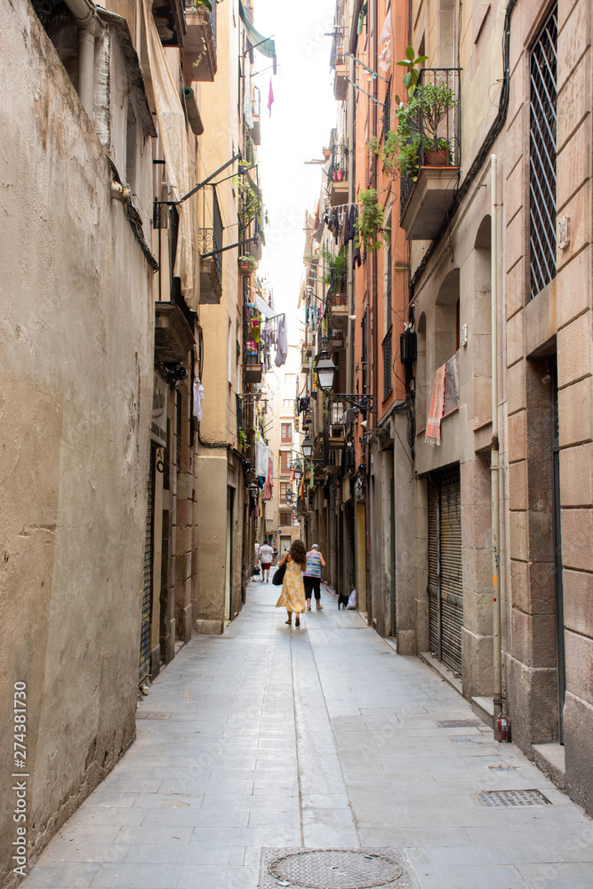 Barcelona, Spain - 25th July 2017 - People or tourists walking through a long alley to the shops