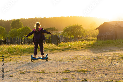 At sunset, a teen girl rides a hoverboard