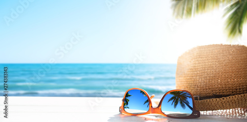Sunny tropical beach vacation background; glasses and palm tree reflex