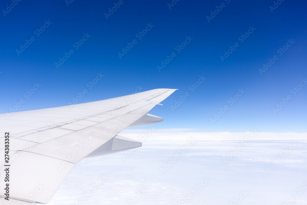 Wing of airplane flying above the clouds in the sky background. Wing of airplane flying above the clouds in the sky background.