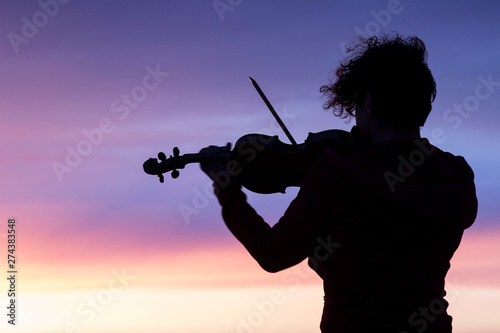 Silhouette of a woman with a violin at sunset.
