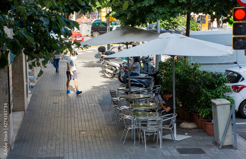 Barcelona, Spain - 26th July 2017 - Cyclist and people sitting outside cafe