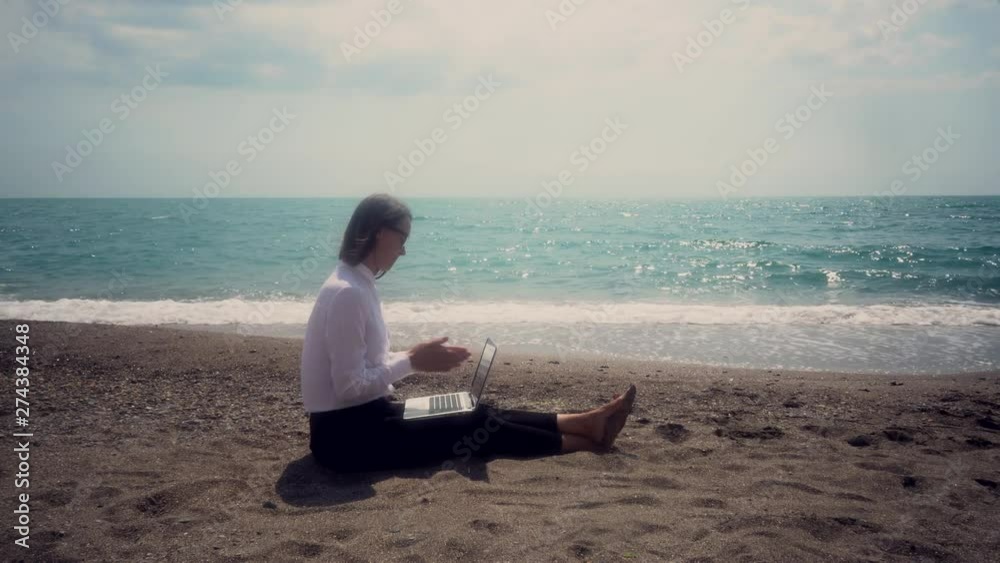 successful business woman with a mobile phone working in a laptop sitting on the beach. concept - vacation. toned image. successful business woman with a mobile phone working in a laptop sitting on the beach. concept - vacation. toned image.