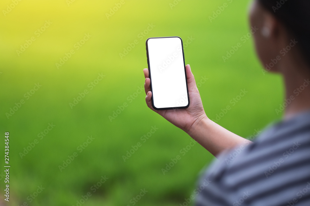 Mockup image of a woman holding black mobile phone with blank desktop screen with blur green nature background