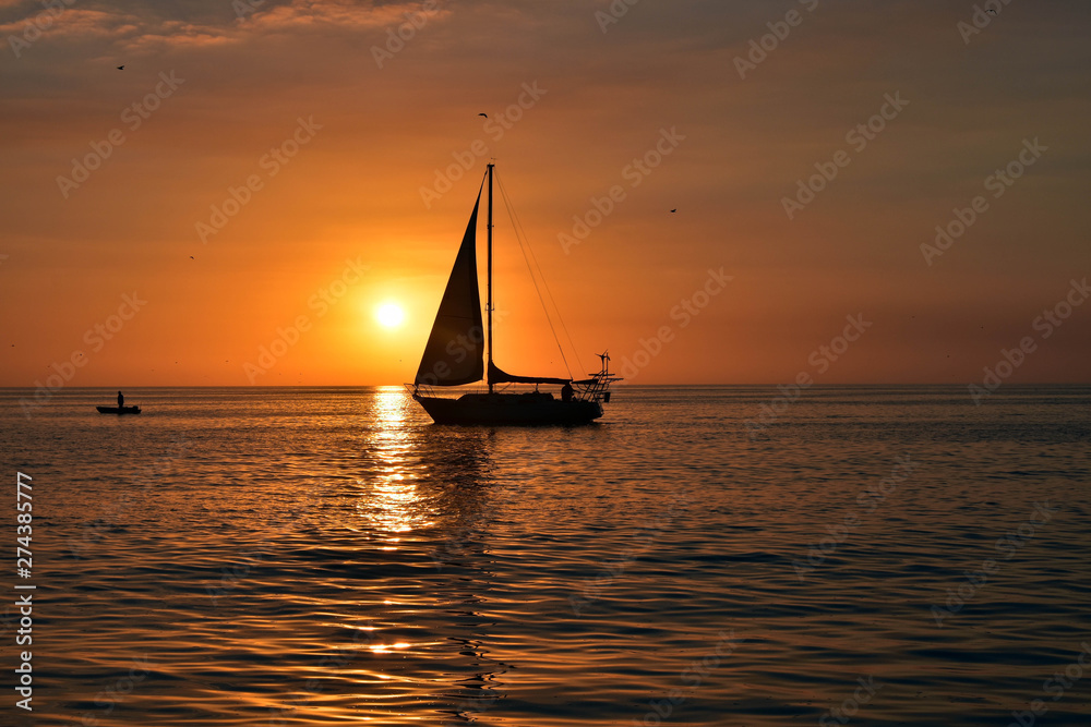 sunset as sail boat sails in front of sun