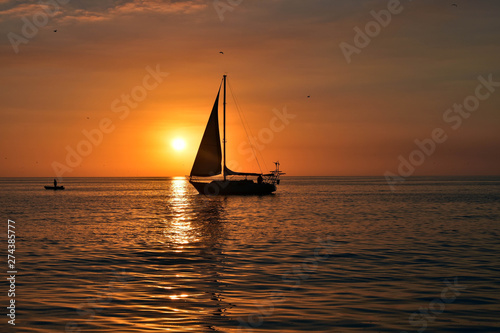 sunset as sail boat sails in front of sun