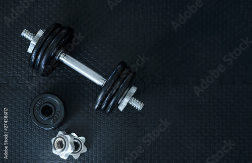 Top view of Iron dumbbells or weights on black floor with copy space for text. Flat lay composition. Health care concept.