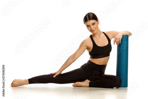 Young beautiful woman posing with blue yoga mat on white background © Jasmina