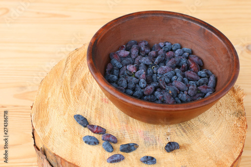 Harvest of Haskap berries, Lonicera caerulea, also calles honeyberries, blue berry honeysuckle or sweetberry honeysuckle, superfood in ceramic bowl on wooden table photo