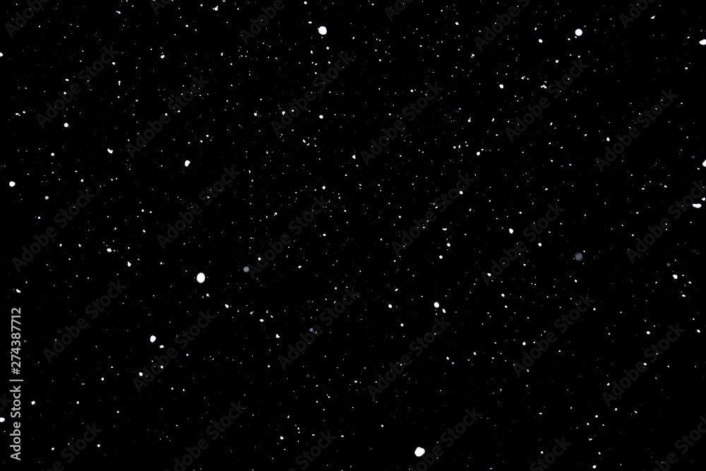 Fototapeta premium falling snow on a black background, snowfall at night, white chaotic spots on a black background