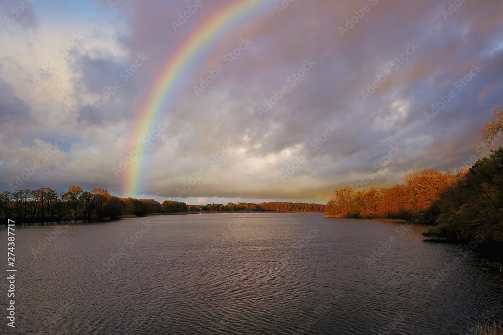 Naklejka premium Colorful rainbow in the sky over lake
