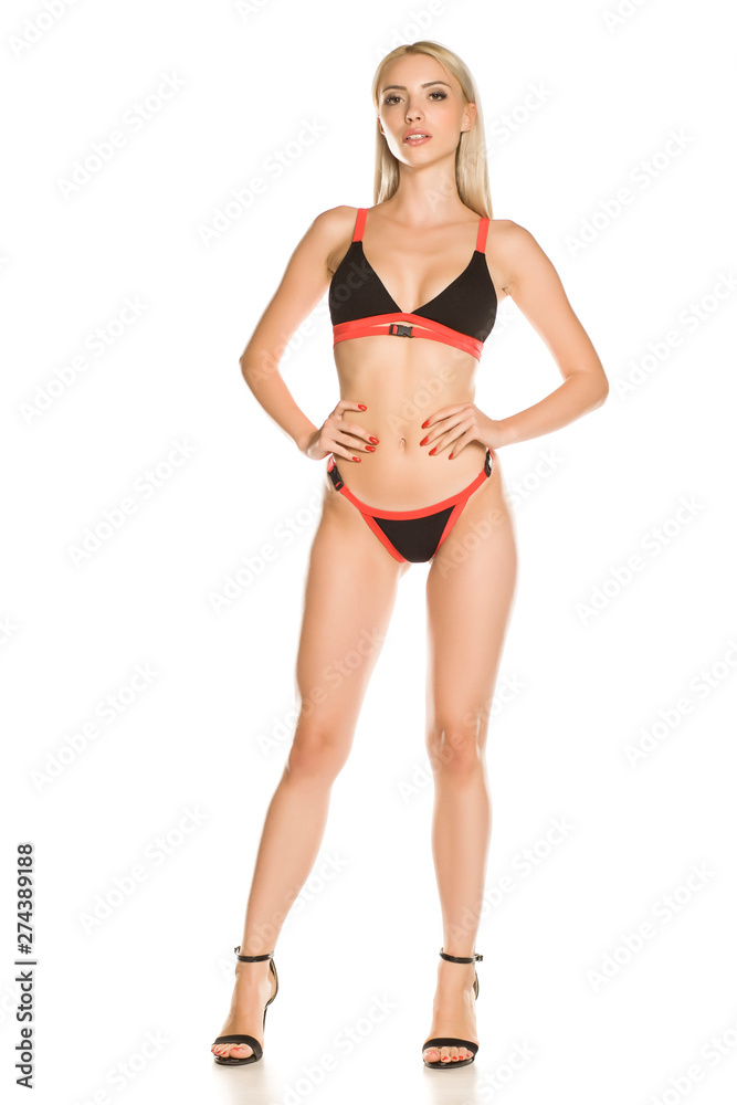 Pretty young lady in black bikini swimsuit and sandals on white background