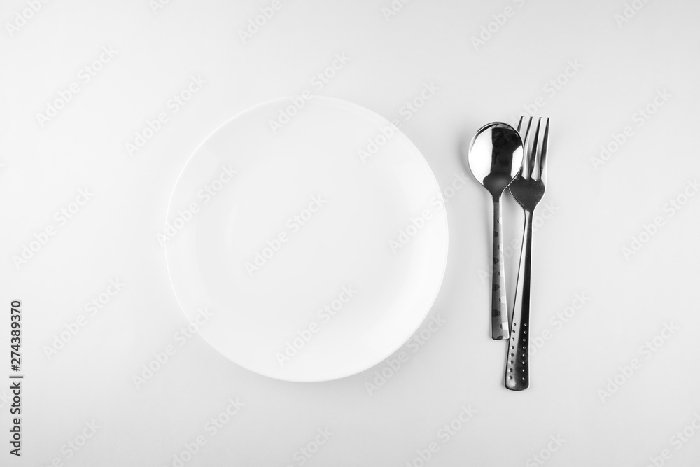 Empty white plate, spoon and knife isolated on white background. diet concept. Empty white plate, spoon and knife isolated on white background. diet concept.