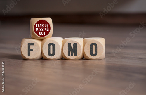 Cubes and dice with FOMO Fear of missing out on wooden background photo