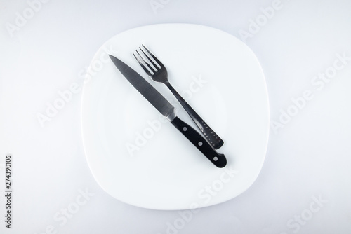 Empty white plate, spoon and knife isolated on white background. diet concept.