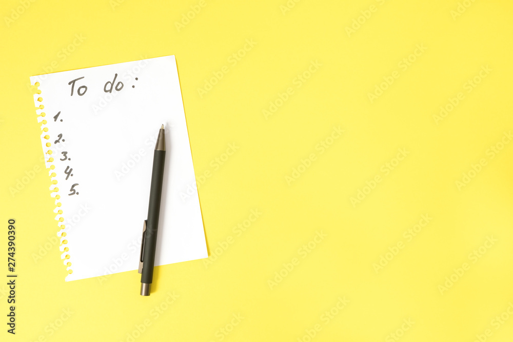 To do list on white sheet torn from spiral notebook and black pen on bright yellow table with copy space, top view To do list on white sheet torn from spiral notebook and black pen on bright yellow table with copy space, top view