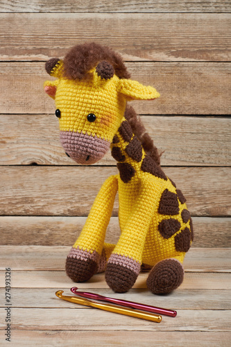 Crocheted toy giraffe on a wooden background photo