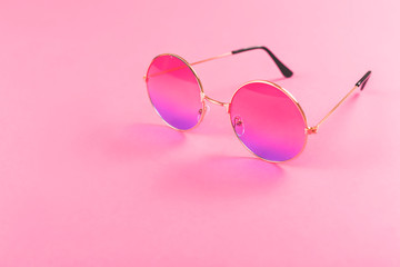 Round summer duotone sunglasses on pink background.