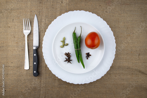 Empty white plate, spoon, knife and spices isolated on jute background. diet concept.