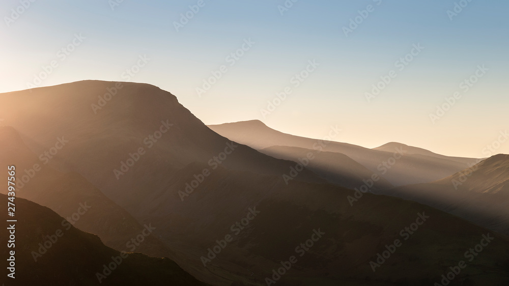 Beautiful Autumn Fall landscape image of sun beams lighting up small area of mountain side in Lake District whilst rest of area is in darkness with Robinson and Dale Head in background Beautiful Autumn Fall landscape image of sun beams lighting up small area of mountain side in Lake District whilst rest of area is in darkness with Robinson and Dale Head in background