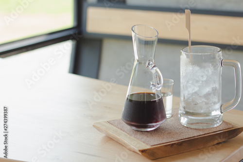 Black coffee cup with ice on wood table in coffee shop. 