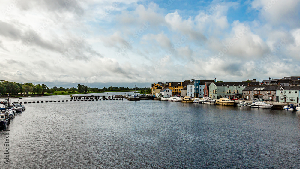 Obraz premium Beautiful view of the river Shannon with boats anchored on the coast and picturesque houses in the Athlone town, wonderful cloudy day in the county of Westmeath, Ireland