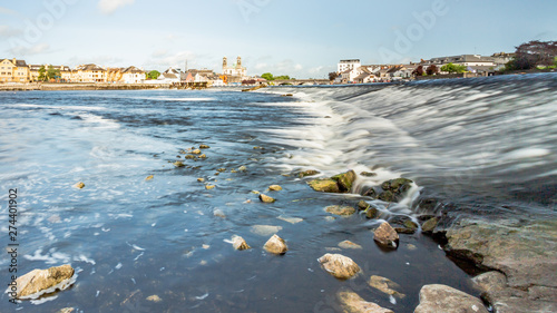 View of the river Shannon with its crystal clear waters and stones on the shore with the town of Athlone in the background, wonderful cloudy day in the county of Westmeath, Ireland photo