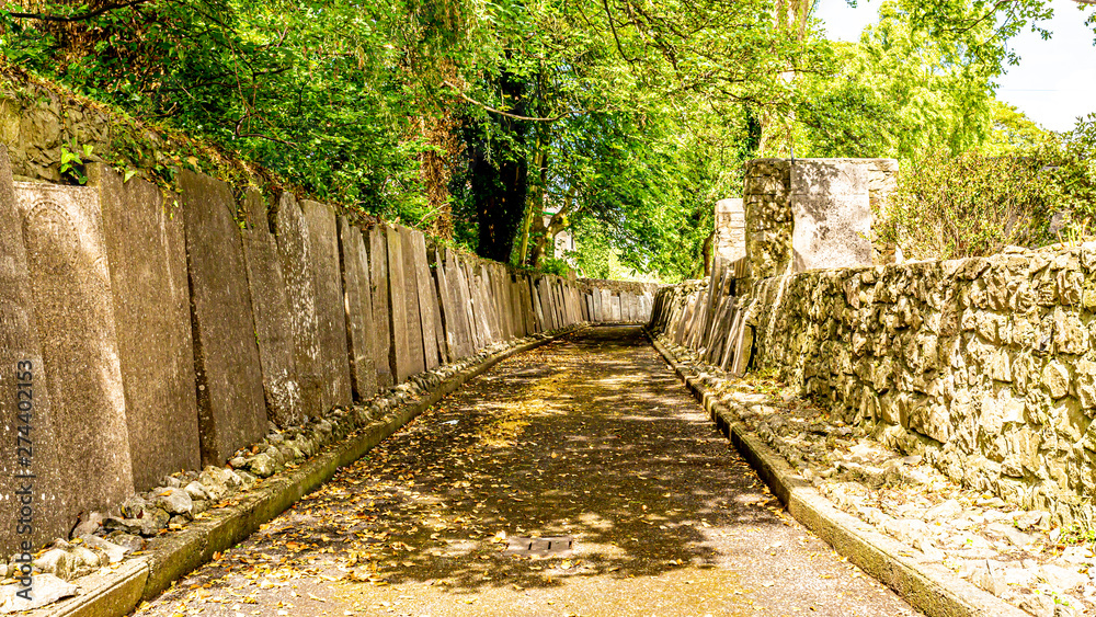 Exterior passageway of Graveyard Abbey with tombstones resting on the walls in the village of Athlone, beautiful sunny spring day in the county of Westmeath, Ireland