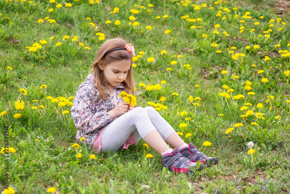 Girl and dandelions / Lovely little girl playing in the spring field full of dandelions Girl and dandelions / Lovely little girl playing in the spring field full of dandelions