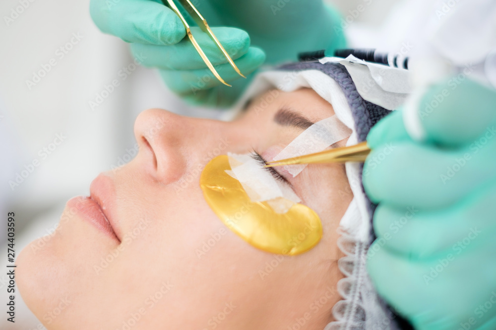 Procedure of eyelash extension in salon by cosmetician