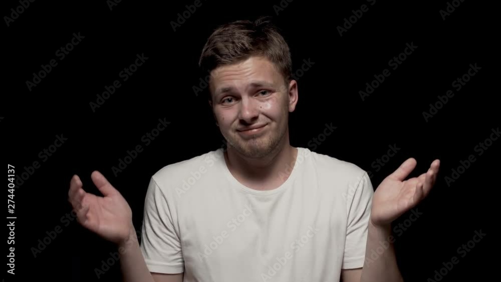 Disappointed caucasian male looking at camera. Close up shot. Black bg. White t-shirt. Disappointed caucasian male looking at camera. Close up shot. Black bg. White t-shirt.