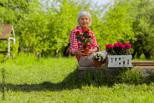Woman sitting near trees in her garden and enjoying flowers © zinkevych