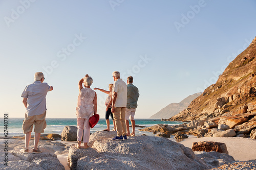 Rear View Of Senior Friends Standing On Rocks On Summer Group Vacation Looking Out To Sea