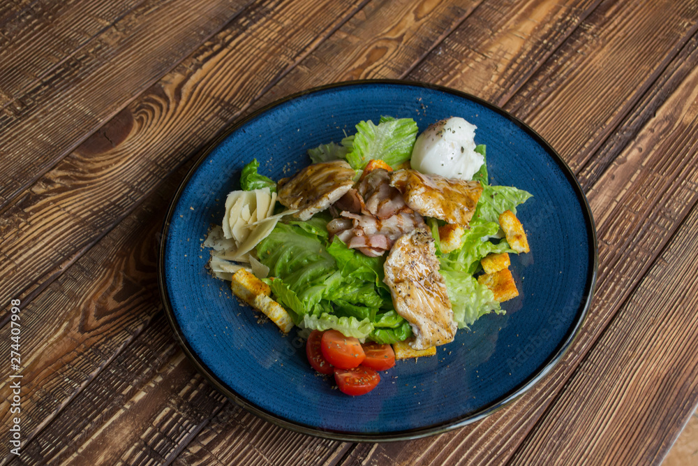 The hot salad with meat on a wooden background. The hot salad with meat on a wooden background.