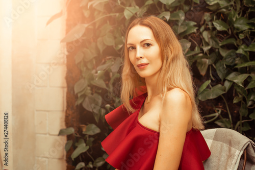 Foto A beautiful young woman in an asymmetrical red-burgundy cocktail dress on one sh