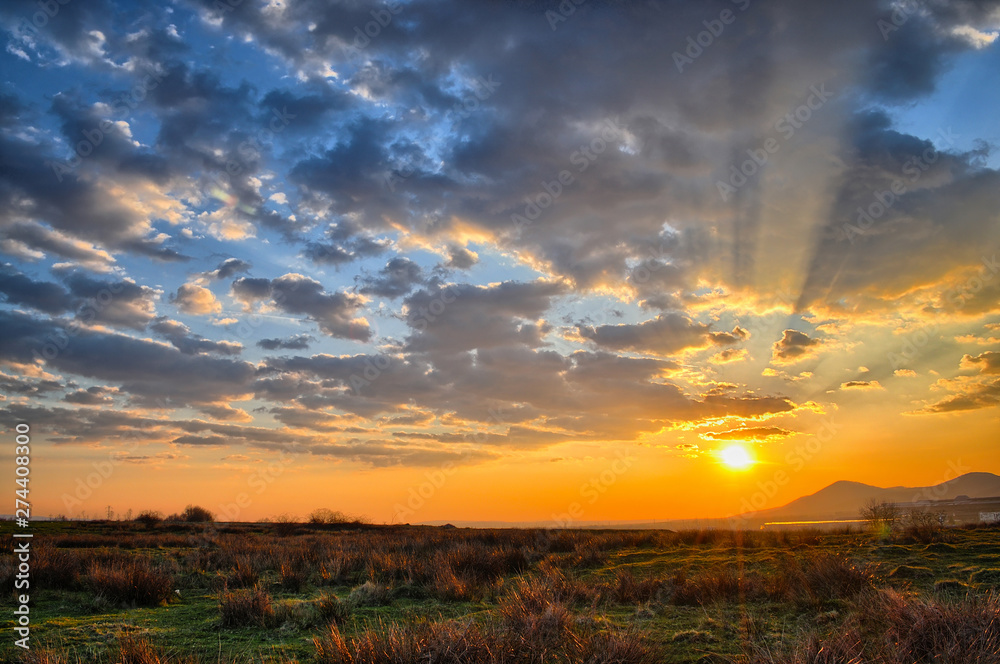 Spring sunset with sunbeams through clouds Spring sunset with sunbeams through clouds